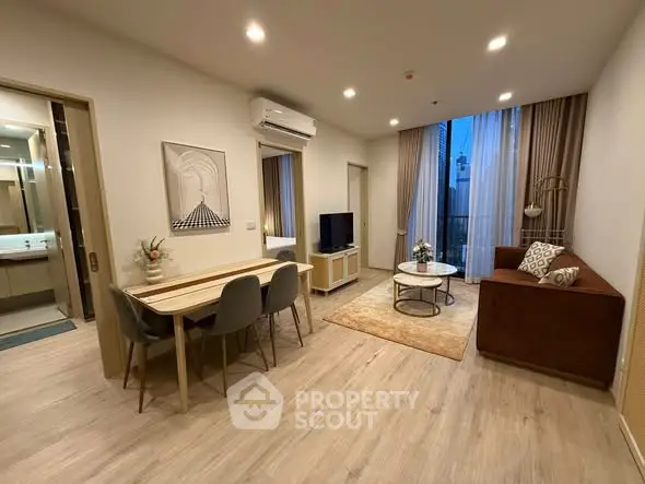 Modern living room with stylish decor, dining area, and cozy seating in a well-lit apartment.