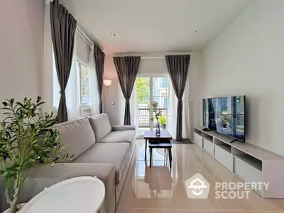 Modern living room with large windows, stylish gray sofa, and sleek TV setup.