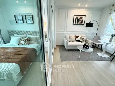 Modern studio apartment with stylish living area and cozy bedroom separated by glass partition.