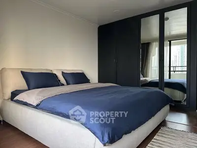 Spacious bedroom with modern decor and mirrored wardrobe in urban apartment.