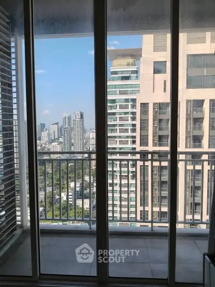 Stunning cityscape view from a modern apartment balcony with glass doors.