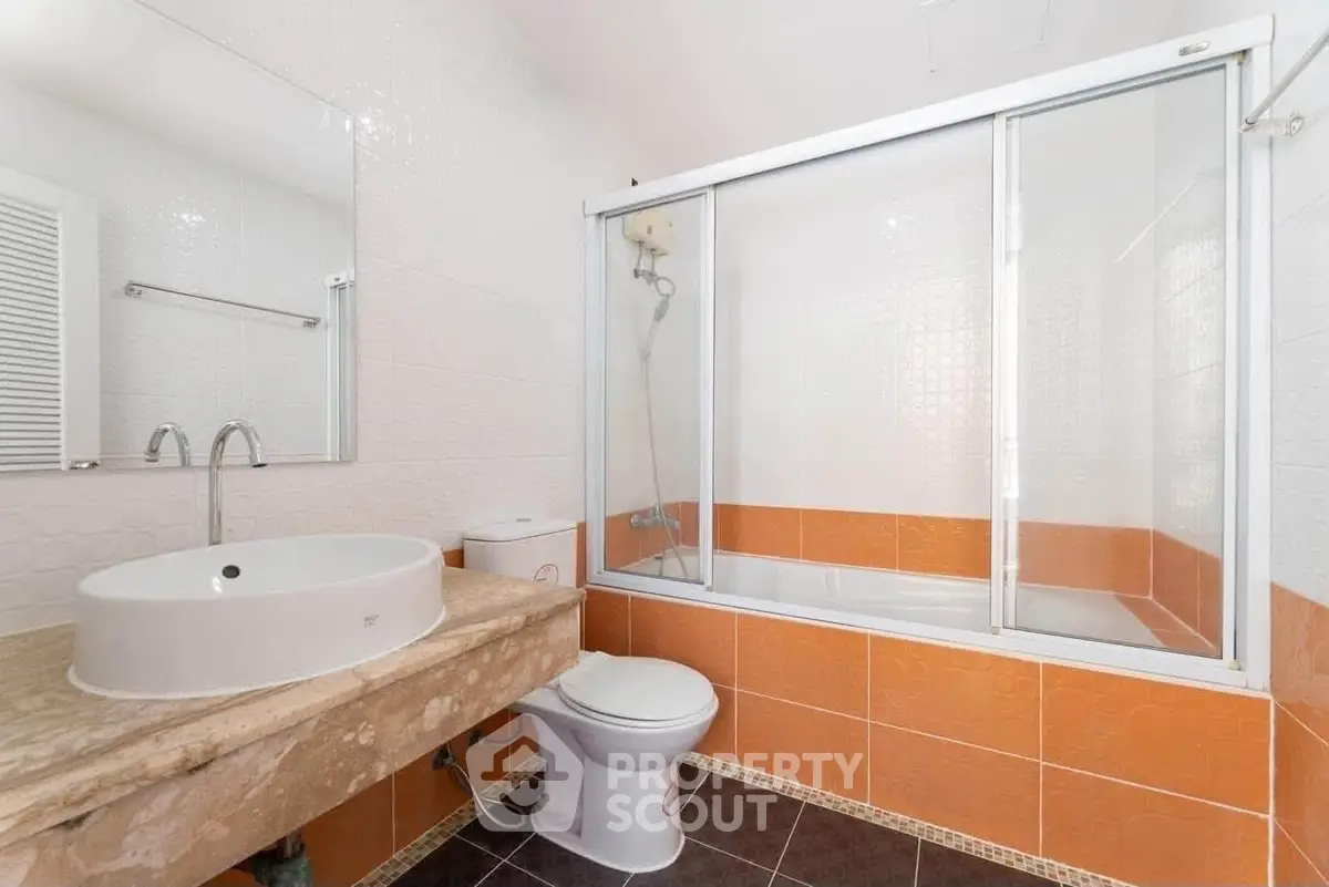 Modern bathroom with orange tiles and glass shower enclosure