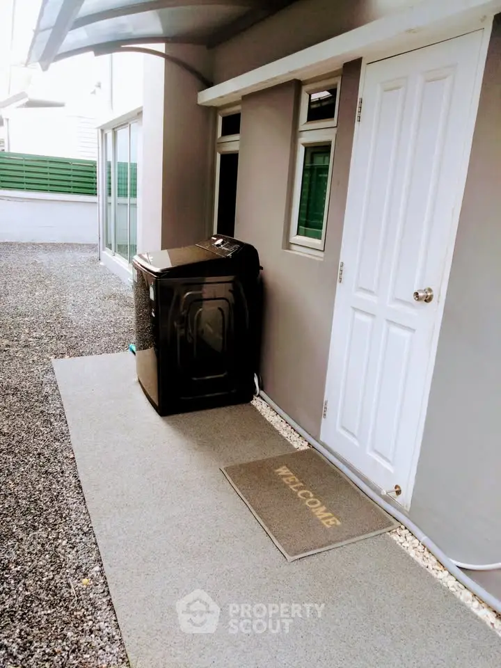 Modern exterior with washing machine and welcome mat, perfect for convenient living.