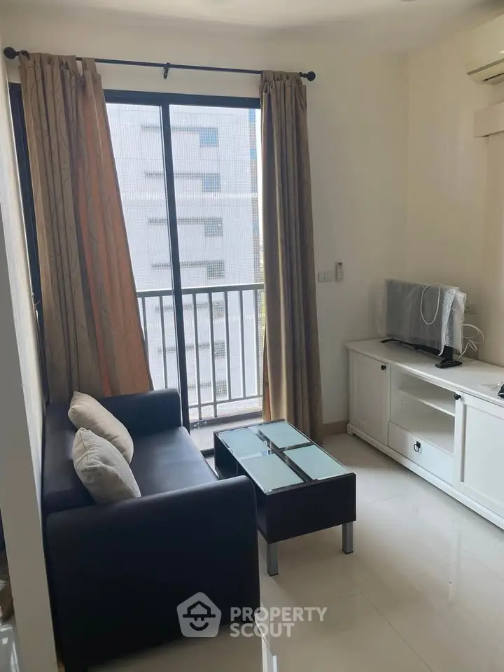 Cozy living room with modern furniture and balcony view in urban apartment.