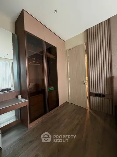 Modern bedroom with sleek wooden flooring and built-in wardrobe