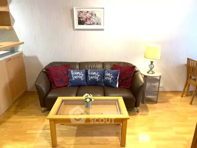 Cozy living room with stylish sofa and decorative pillows, warm lighting, and wooden flooring.