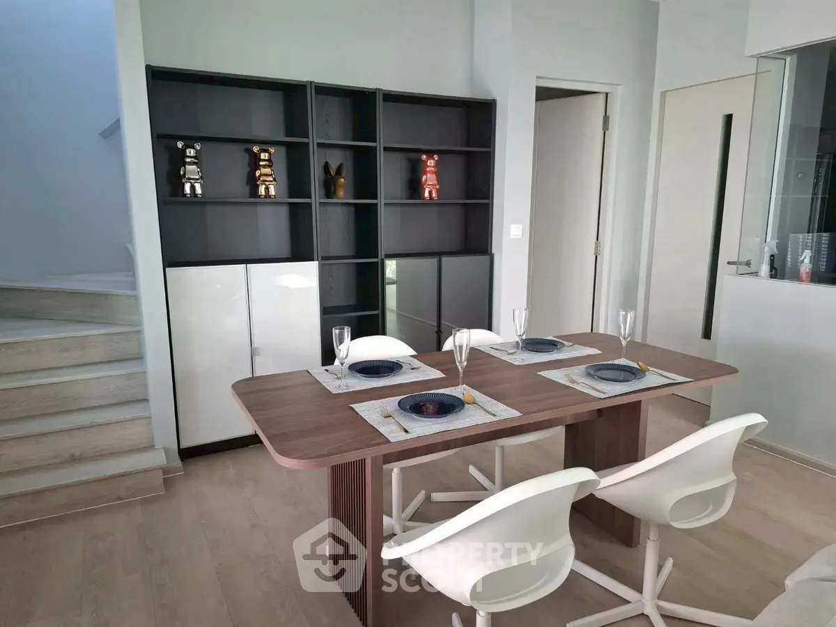 Modern dining area with sleek table and chairs, stylish shelving, and elegant decor.