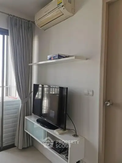 Modern living room with air conditioning and TV unit, featuring sleek design and natural light.