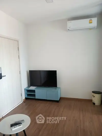 Modern living room with minimalist decor, featuring a sleek TV stand and air conditioning unit.