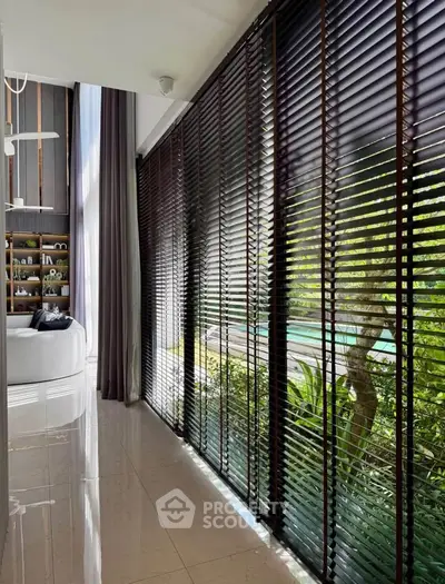 Luxurious living room with floor-to-ceiling windows and garden view, featuring elegant blinds and modern decor.