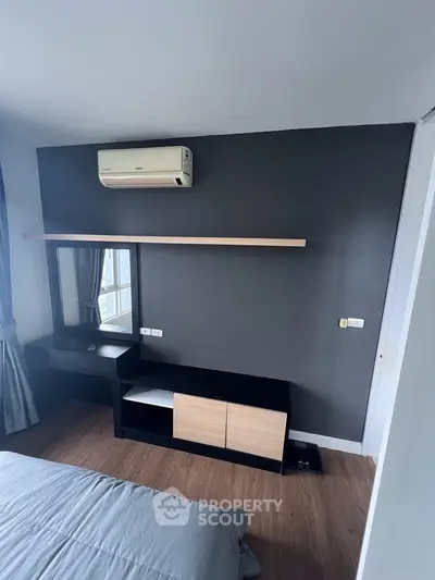 Modern bedroom with sleek furniture and air conditioning, featuring a stylish dark accent wall.