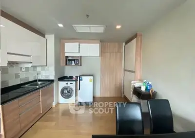 Modern kitchen with wooden cabinets, washing machine, and dining area in a sleek apartment.