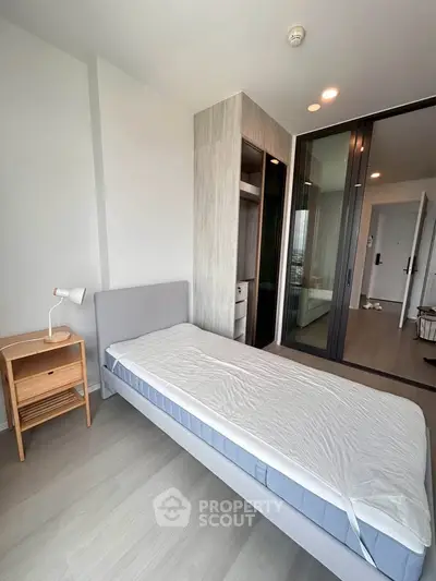 Modern bedroom with minimalist design and large sliding glass doors in a high-rise apartment.