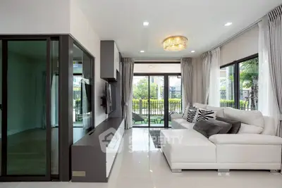 Modern living room with sleek design and large windows opening to a garden view.