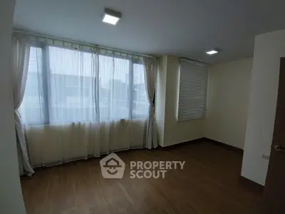 Spacious empty room with large windows and wooden flooring in modern apartment