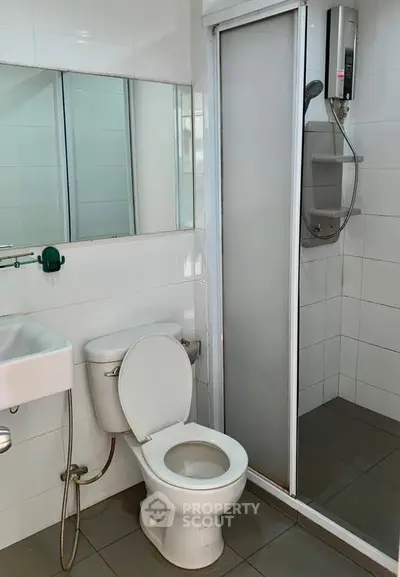Modern bathroom with shower and toilet in a sleek, tiled design.