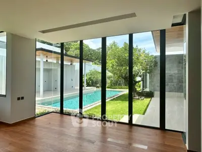 Luxurious modern living room with floor-to-ceiling windows overlooking a private pool and lush garden.