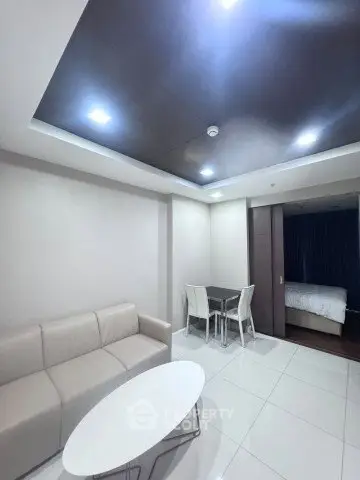 Modern living room with sleek furniture and adjacent bedroom in open layout apartment.