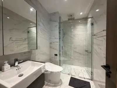 Luxurious modern bathroom with glass shower and elegant marble finishes.