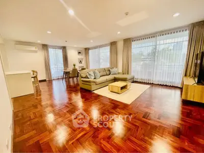 Spacious living room with elegant wooden flooring and large windows for natural light.