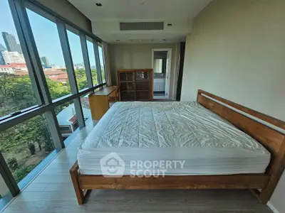 Spacious bedroom with large windows offering stunning city views and natural light.