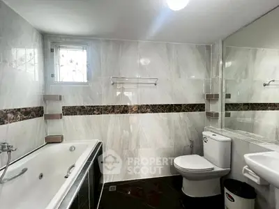 Spacious modern bathroom with elegant marble tiles and luxurious bathtub.