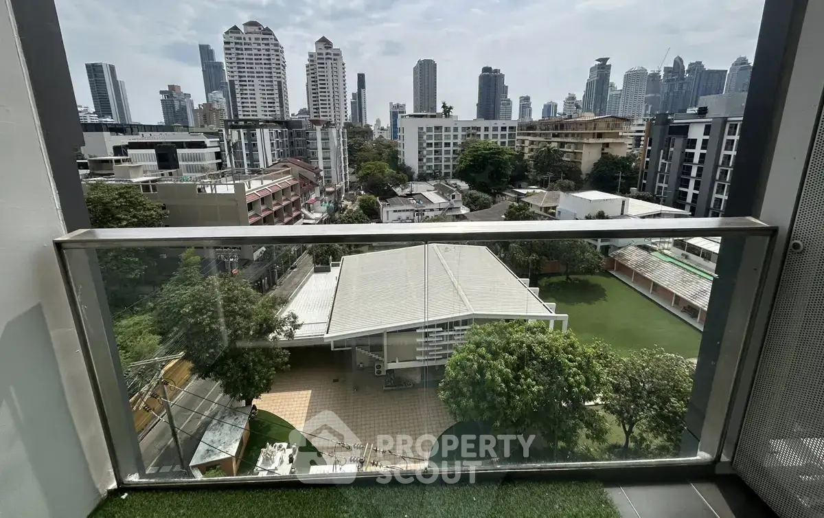 Stunning cityscape view from a modern balcony overlooking lush greenery and urban skyline.