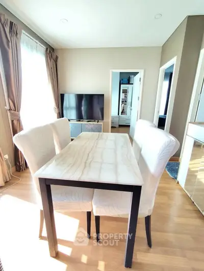 Bright dining area with elegant table and chairs, large window, and modern TV setup.