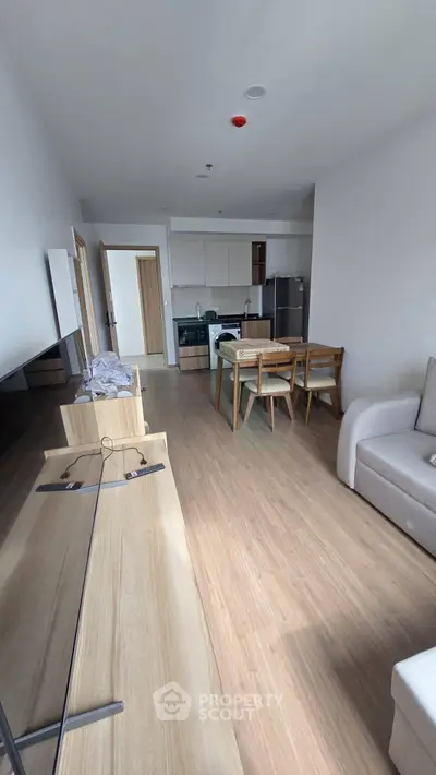 Modern open-plan living room with kitchen, featuring sleek furniture and wooden flooring.