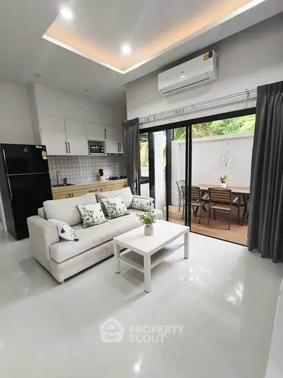 Modern open-plan living room with kitchen and outdoor dining area, featuring sleek design and natural light.