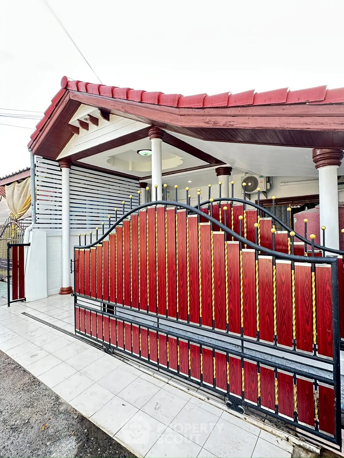 Charming house entrance with elegant red gate and tiled pathway