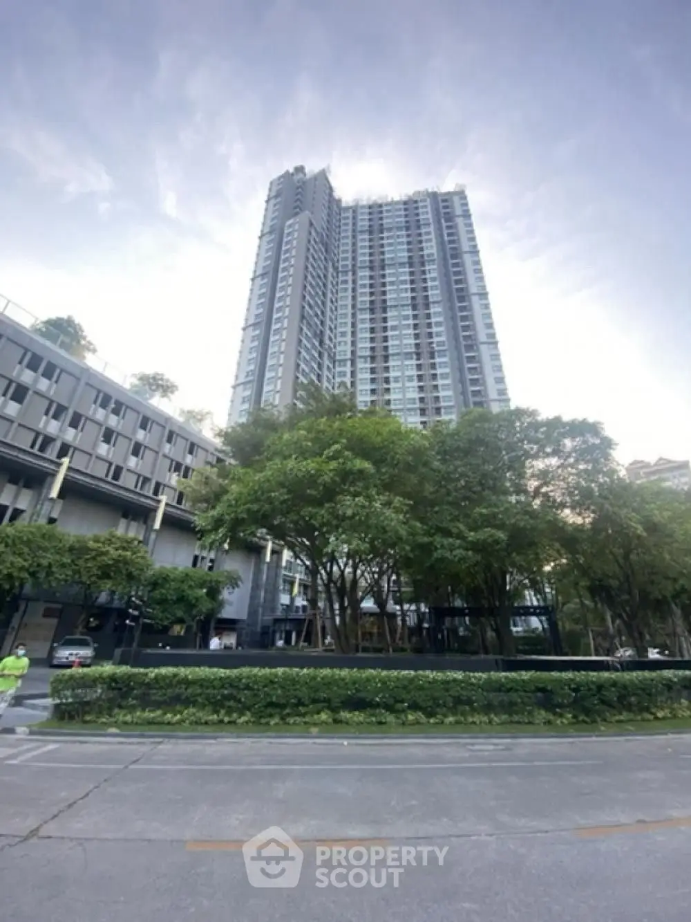 Modern high-rise building with lush greenery and street view