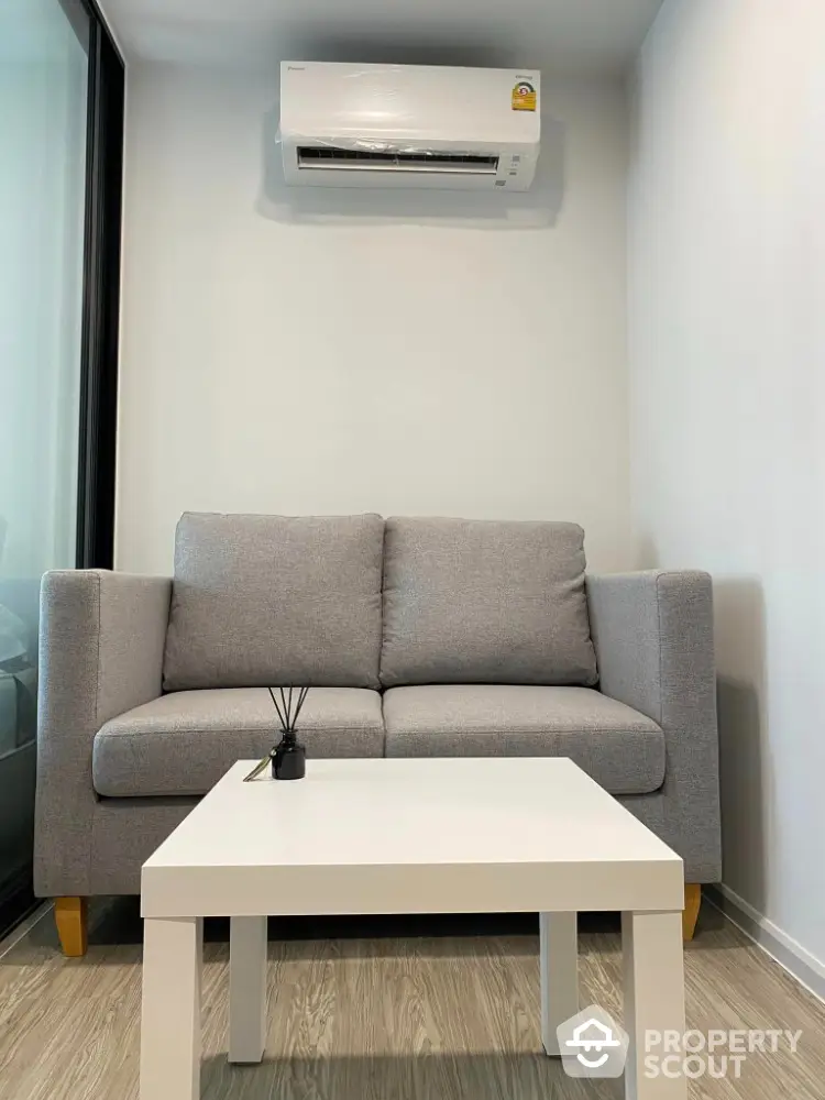 Modern living room with gray sofa and white coffee table under air conditioner