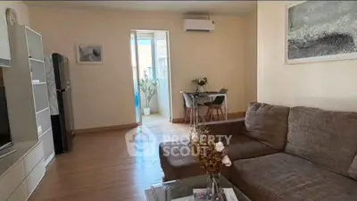 Cozy living room with modern decor and air conditioning, featuring a comfortable sofa and dining area.