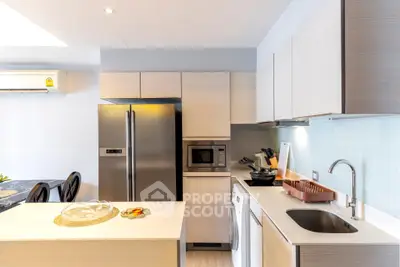 Modern kitchen with sleek appliances and stylish cabinetry, featuring a washing machine and stainless steel fridge.