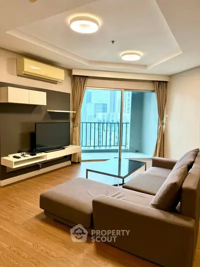 Modern living room with large sofa and city view balcony in high-rise apartment.