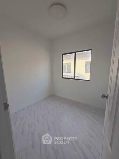 Bright and minimalist bedroom with tiled flooring and a window view.