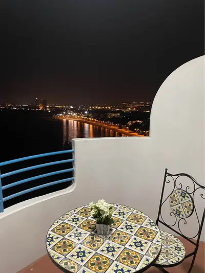 Stunning balcony view with decorative table overlooking city lights and ocean at night.