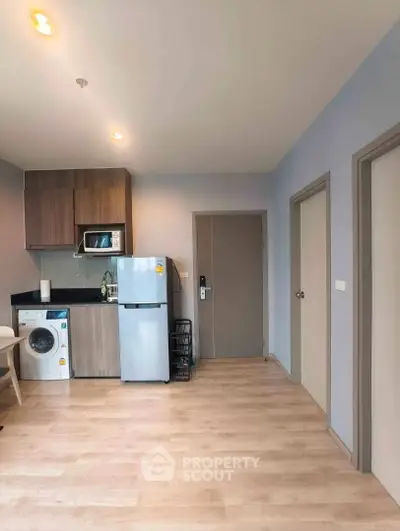 Modern kitchen with sleek appliances and wooden cabinetry in a cozy apartment setting.