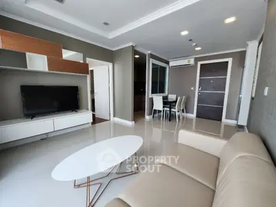 Modern living room with sleek furniture and open layout, featuring a stylish TV unit and elegant dining area.