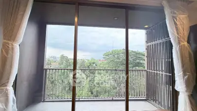 Spacious balcony with serene green view through large glass doors in modern apartment.