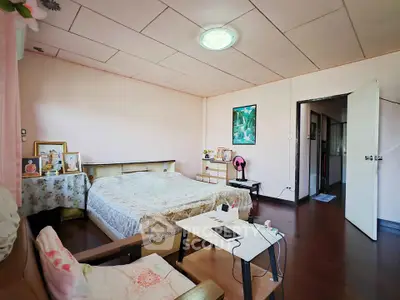 Cozy bedroom with wooden flooring and soft pink walls, featuring a comfortable bed and charming decor.