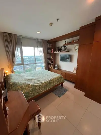 Spacious bedroom with large window offering stunning city views, featuring elegant wooden furniture and cozy decor.