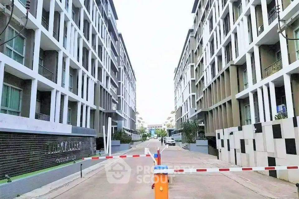 Modern apartment complex entrance with security barrier and contemporary architecture.