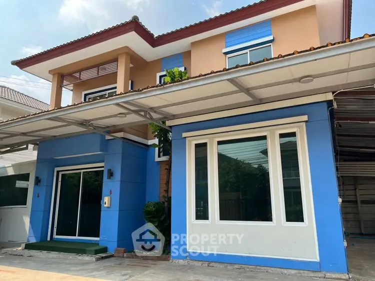 Charming two-story house with vibrant blue facade and spacious driveway