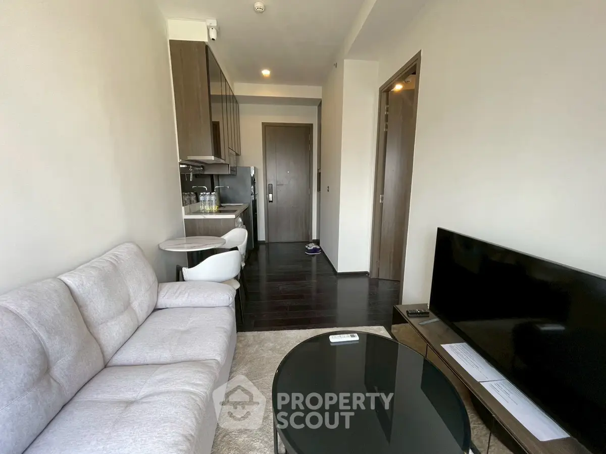 Modern living room with sleek furniture and open kitchen layout in a stylish apartment.