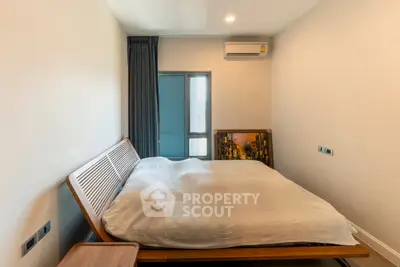 Modern bedroom with sleek design and natural light, featuring a stylish bed and air conditioning.