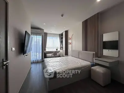 Modern bedroom with sleek design, featuring a large bed, wall-mounted TV, and a bright window view.