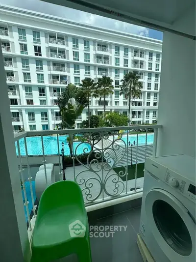 Charming balcony view overlooking a luxurious pool and modern apartment complex, featuring a convenient washing machine.