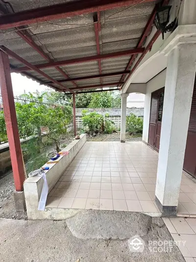 Charming covered patio with tiled flooring and garden view, perfect for outdoor relaxation and gatherings.